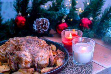 Christmas chicken baked with potatoes, herbs, with the decoration of the set table. Christmas dinner, a festive dish. Side view of the table, close-up. Selective focusの写真素材