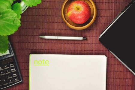 Desk with work tools in office, apple on wooden bowlの写真素材