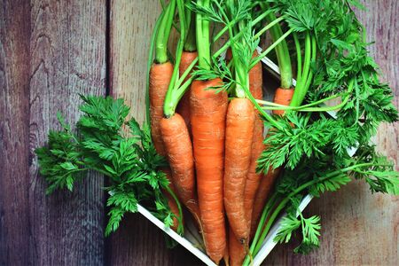 Bunch of carrots in white box, rustic wooden backgroundの写真素材