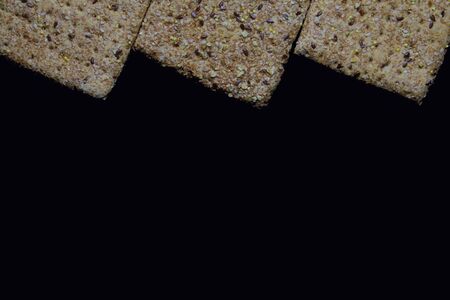 Seeds and cereals in square breads, on dark backgroundの写真素材