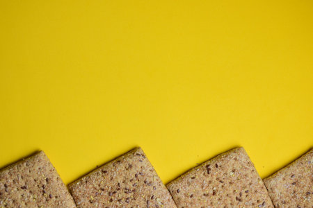Square bread with cereals and seeds on yellow backgroundの写真素材