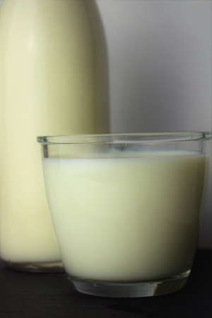 Close up, glass of milk, next to it part of a bottleの写真素材