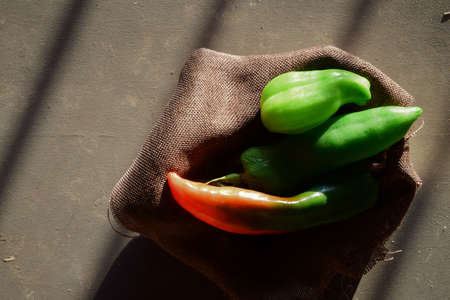 Fresh natural peppers, on a cloth inside a box, entrance light through the windowの写真素材