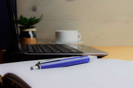 Pen on notebook, background work area with laptopの写真素材