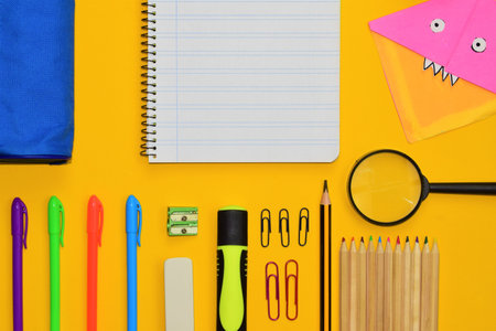 Varied school supplies. Figures made with paper, origami, all on a yellow background and space for textの写真素材