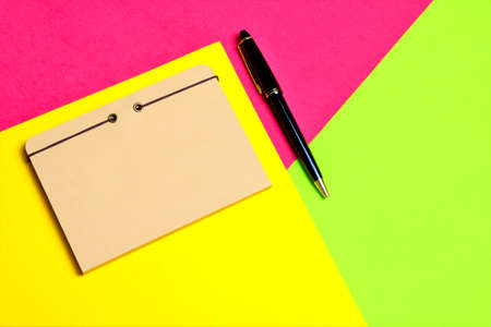 Notebook and black pen with gold details, on a striking tricolor abstract background.の写真素材