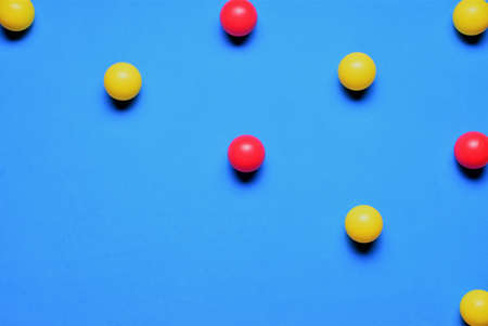 Small colored balls, red and yellow, on a blue background, placed in line, space for textの写真素材