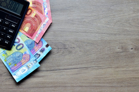 On the table, euro bills and part of a calculator, side space for text
