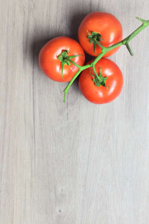 Red tomato branches on wooden table, space for textの写真素材