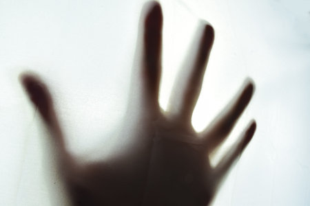 Hand behind a light cloth, expressing panic