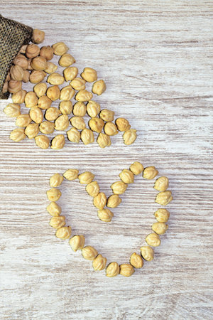 Chickpeas, vegetables very beneficial for the body, on a wooden table in the shape of a heart.