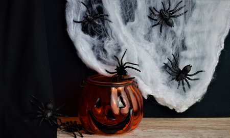 Scary background, panic spiders around, cobwebs and halloween pumpkin, representing the famous...