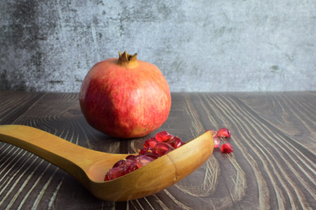 Fruit, pomegranate grains in wooden spoon, on rustic wooden table.の写真素材