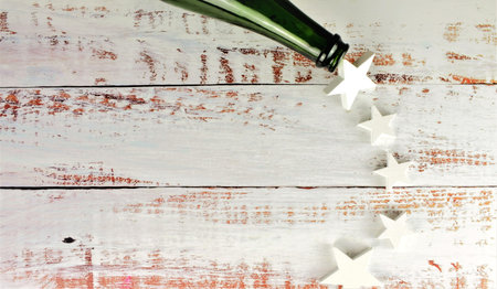 Part of a bottle scattering white stars on rustic wooden table