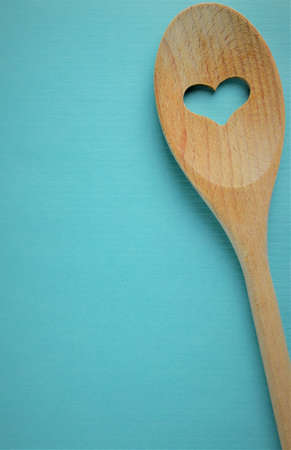Blue kraft paper background, wooden spoon with heart, space for text or idea.の写真素材