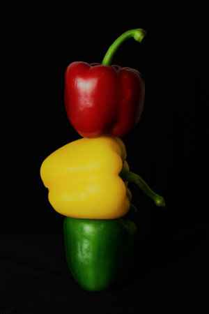 Peppers in three colors in a row, mounted together, on a black background.