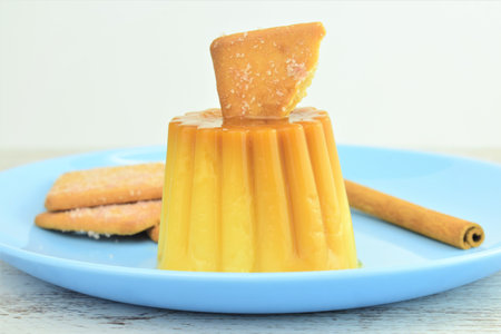 Flan with cinnamon cookie, served in a blue dish