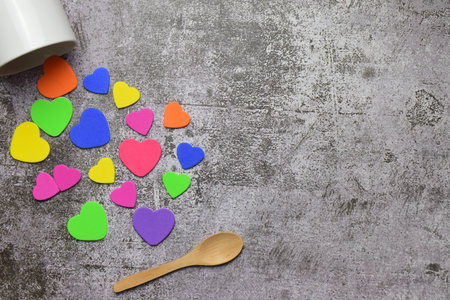 Valentine, love, special day. Multi-colored hearts, with a white cup next to it. Stone background...
