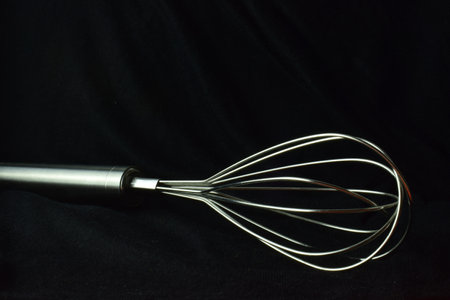 Whisk rod, kitchen utensil on black background. Copy space.の写真素材