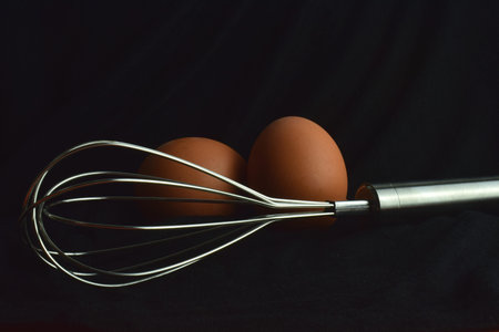 Whisk rod, kitchen utensil on black background.