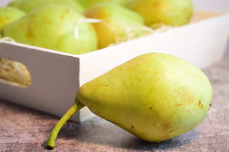 Green pear with more units at the bottom, inside a white wooden box.の写真素材