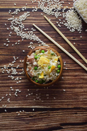 Rice three delights, in a wooden bowl, accompanied by long chopsticks. Copy space.の写真素材