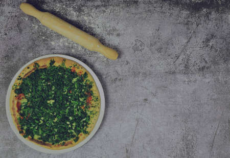 On gray stone, spinach pizza and rolling pin. Zenith view. Copy space.の写真素材