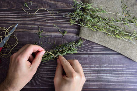 Handling of rosemary branches, putting a rope. Rustic wooden table.の写真素材