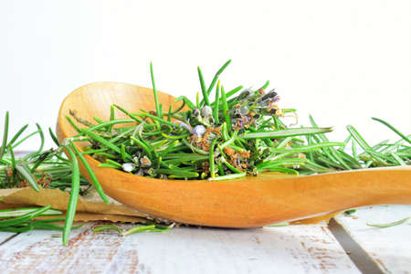 Rosemary leaves in wooden spoon, on rustic white wooden boards.の写真素材