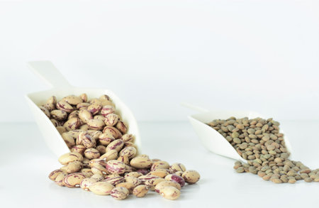 Shovels with assorted legumes, beans, chickpeas and lentils, on white background.