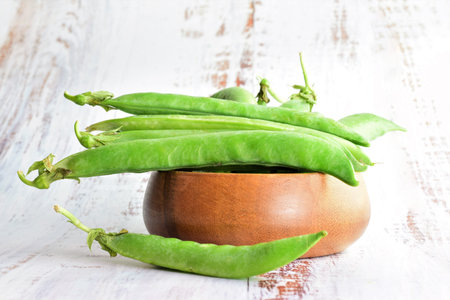 Close up. Peas in a wooden bowl, on a light colored table, copy space.