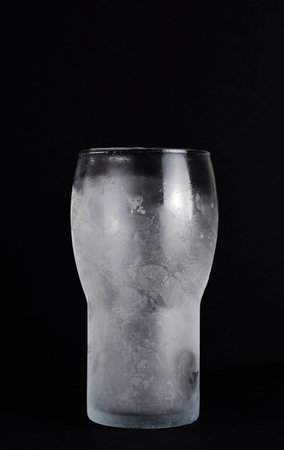 Tall glass, cold, on black background. Copy space.