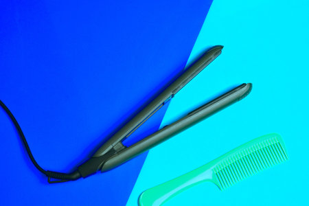 Hair straightener with isolated ceramic plates together with a long comb, bicolor background. Copy...