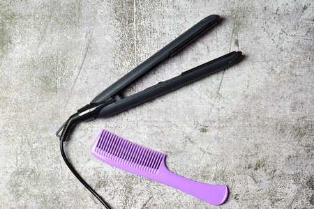 Hair straightener with isolated ceramic plates together with a long comb, on a stone background.の写真素材
