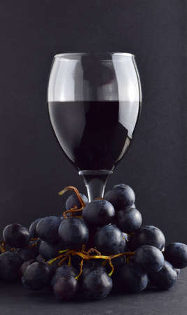 Wine glass and black grapes. Dark background and copy space.の写真素材