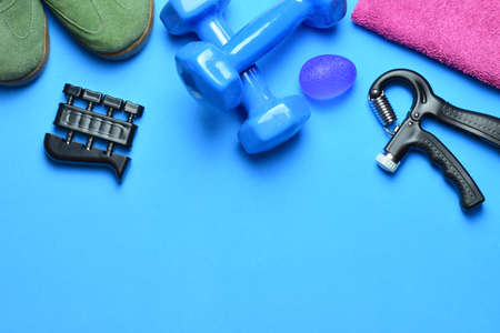 Dumbbells, manual training grip and various accessories, on a blue background. Zenith view and copy space.の写真素材