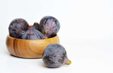 Close up, fruit. Fig on white background and more behind in wooden bowl.の写真素材