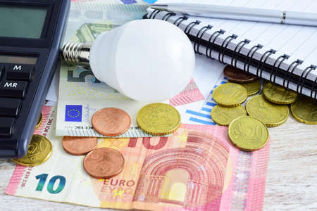 Electricity and energy tax expenses. Lightbulb, scattered money, euros, consumption graph, calculator. Economic concept.の写真素材