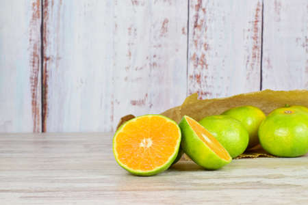 Tangerines with green skin on wood and a background of light-colored rustic boards.の写真素材