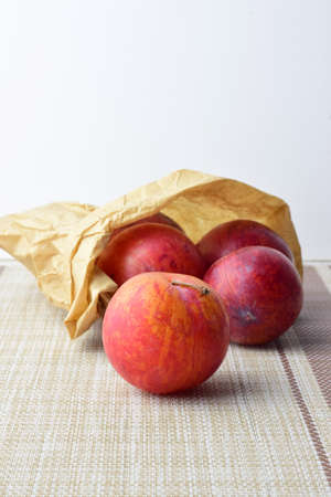 Vertical shot, plums red scattered on tablecloth. Copy space.の写真素材