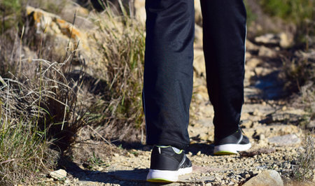 Young person, walk through the mountain, dirt road and vegetation on the sides.