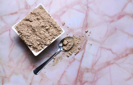 Zenith view, spoon with chocolate powder, next to small porcelain bowl on marble with abstract...
