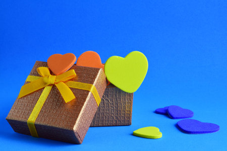 Love, Valentine's Day. Colored hearts inside a gift box and scattered on a blue background.