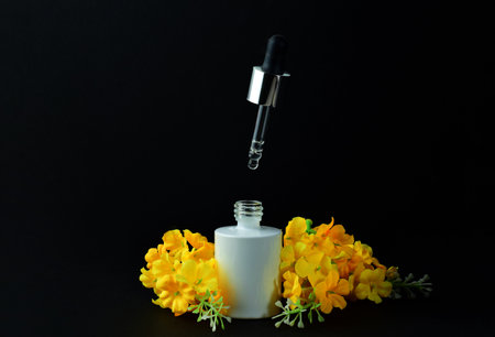 Cosmetic dropper in the air, from underneath, its container, dark background, decorative outline.の写真素材