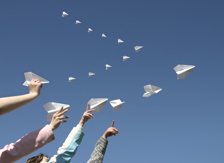 The Children hands send skyward small paper aeroplanes.の写真素材