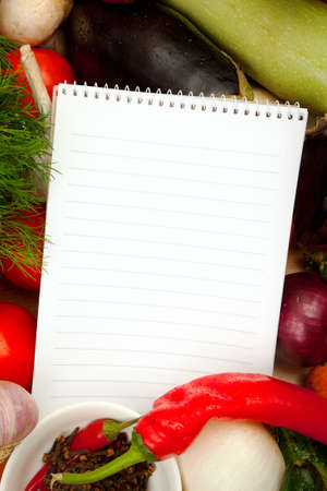 This is a notebook of paper on a background of fresh vegetables. This recipe is delicious and healthy dishes.の写真素材
