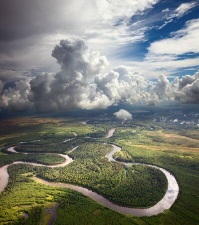 Aerial view of forest the river during summer day on background of great white clouds. の写真素材