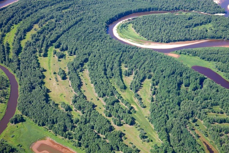 Aerial view of forest river over the summer woodlands during a flight の写真素材