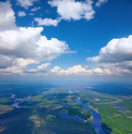 Aerial view of forest the river during summer day on background of great white clouds の写真素材
