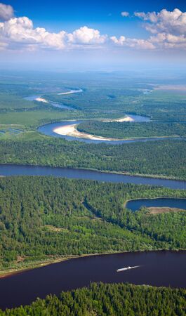Aerial view of forest the river during summer day on background of great white clouds  The ship with barge moves along the river の写真素材